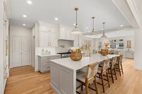 a kitchen with stainless steel appliances kitchen island granite countertop a table chairs and a refrigerator