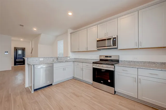 a kitchen with stainless steel appliances granite countertop a sink and a stove