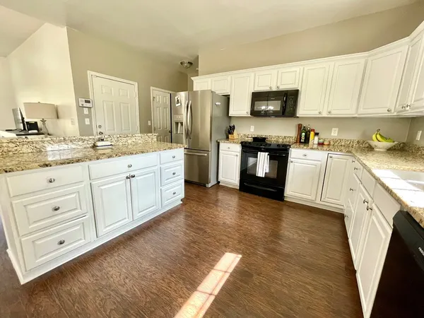 a kitchen with stainless steel appliances granite countertop white cabinets a sink a stove a refrigerator and white cabinets