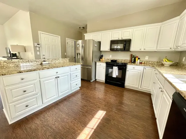 a kitchen with stainless steel appliances granite countertop white cabinets a sink a stove a refrigerator and white cabinets