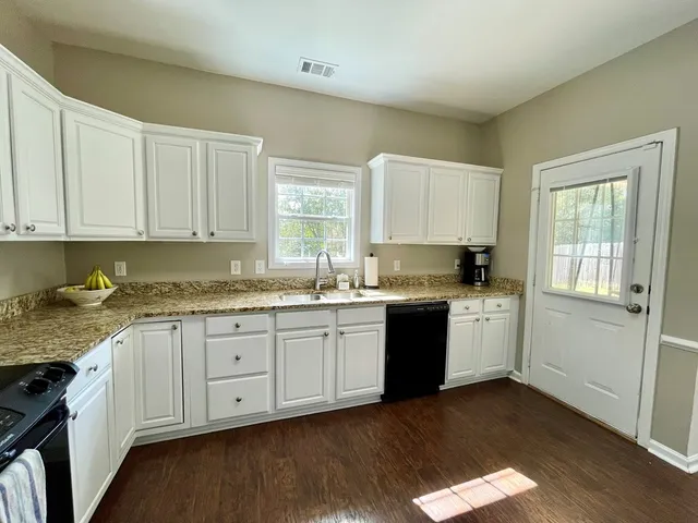 a kitchen with granite countertop cabinets stainless steel appliances a sink and a window