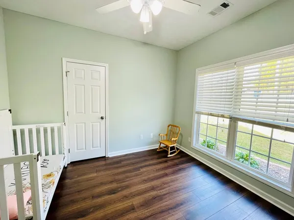 a view of empty room with wooden floor and fan