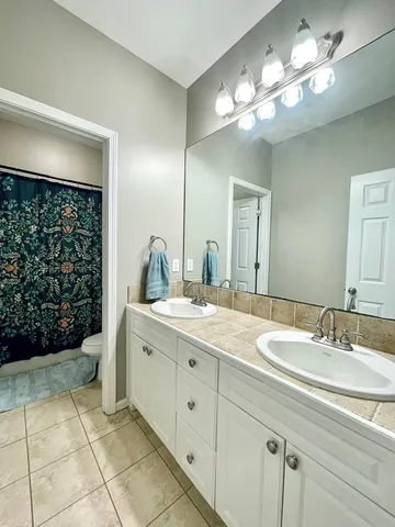 a bathroom with a granite countertop sink a toilet and a mirror