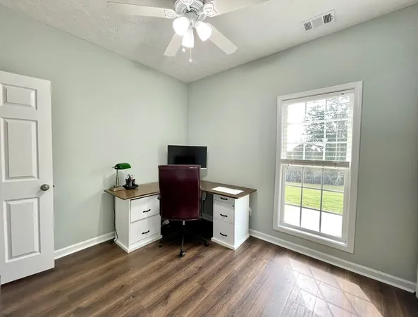 a view of workspace with wooden floor windows and fan