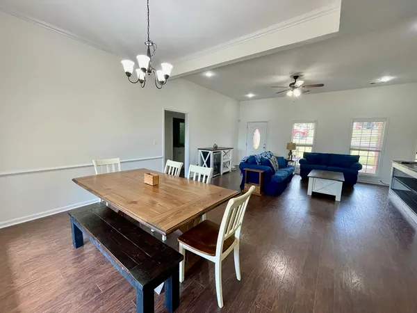 a dining room with wooden floor a chandelier a wooden table and chairs