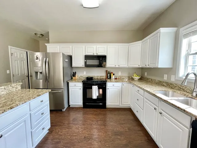 a kitchen with granite countertop a refrigerator stove top oven and sink