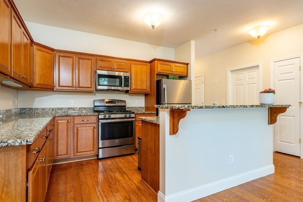 45 Grey Hawk Drive, Unit 45 Mashpee, MA 02649 - Photo 7 of 21 a kitchen with granite countertop a refrigerator and a stove top oven