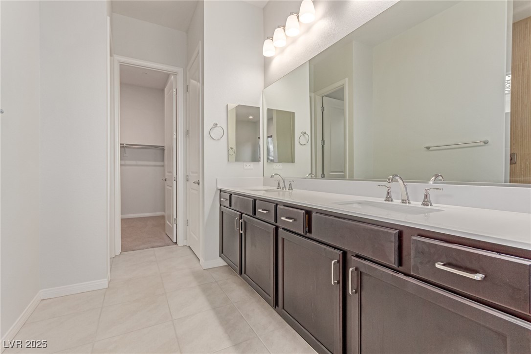 298 Nine Mile Creek Drive Las Vegas, NV 89138 - Photo 11 of 30 Full bathroom featuring double vanity, light tile patterned flooring, and a walk in closet