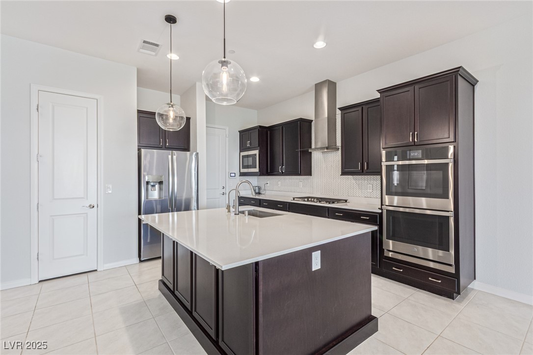 298 Nine Mile Creek Drive Las Vegas, NV 89138 - Photo 6 of 30 Kitchen featuring appliances with stainless steel finishes, backsplash, decorative light fixtures, dark brown cabinets, and light tile patterned floors