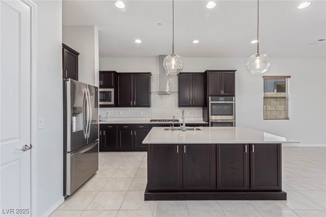 298 Nine Mile Creek Drive Las Vegas, NV 89138 - Photo 7 of 30 Kitchen with backsplash, stainless steel appliances, light tile patterned flooring, dark brown cabinets, and decorative light fixtures