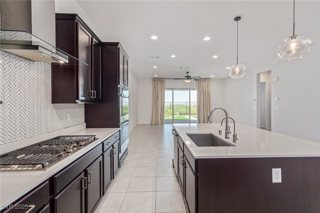 298 Nine Mile Creek Drive Las Vegas, NV 89138 - Photo 8 of 30 Kitchen featuring dark brown cabinetry, wall chimney range hood, decorative light fixtures, stainless steel appliances, and recessed lighting