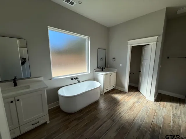 a spacious bathroom with a double vanity sink mirror and bathtub