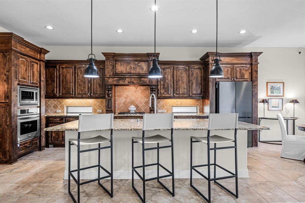 8 Center Court Heath, TX 75032 - Photo 14 of 34 a kitchen with stainless steel appliances kitchen island granite countertop a stove a refrigerator and chairs