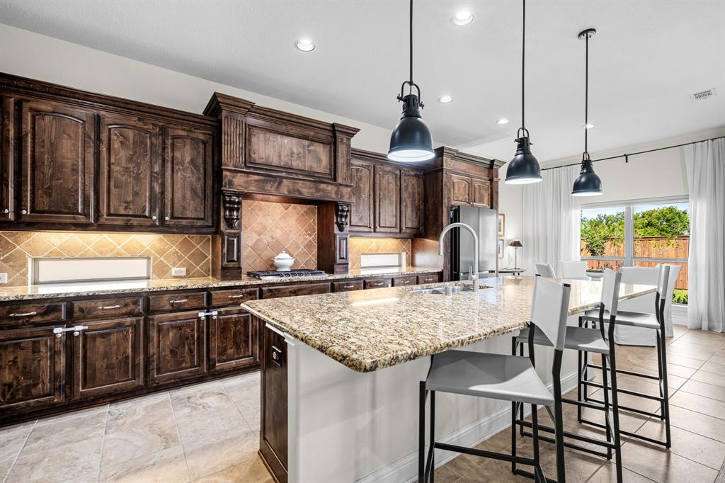 8 Center Court Heath, TX 75032 - Photo 15 of 34 a kitchen with stainless steel appliances granite countertop a stove top oven a sink a dining table and chairs with wooden floor