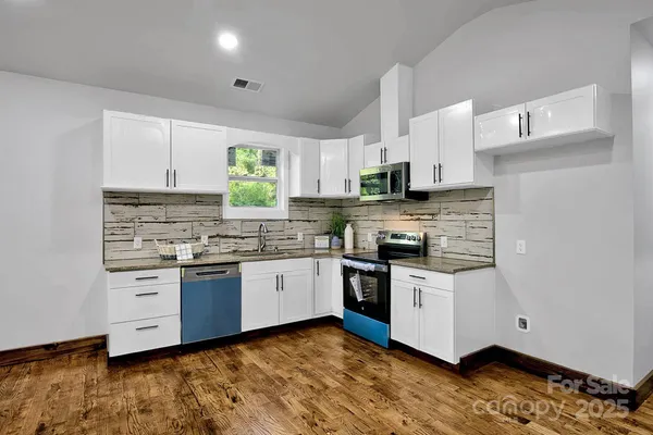 a kitchen with stainless steel appliances a sink a stove a refrigerator cabinets and a window