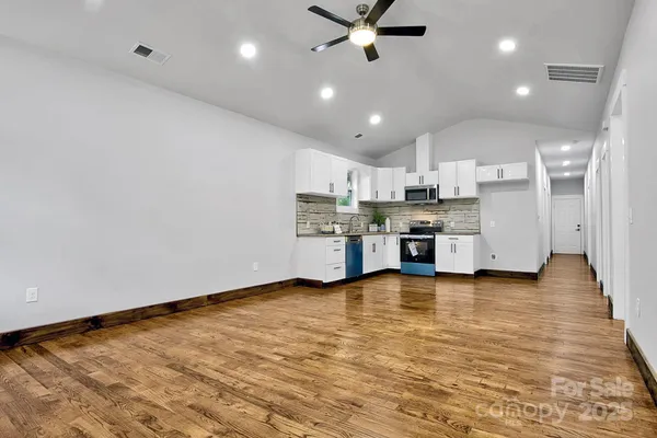a view of an empty room with window and wooden floor