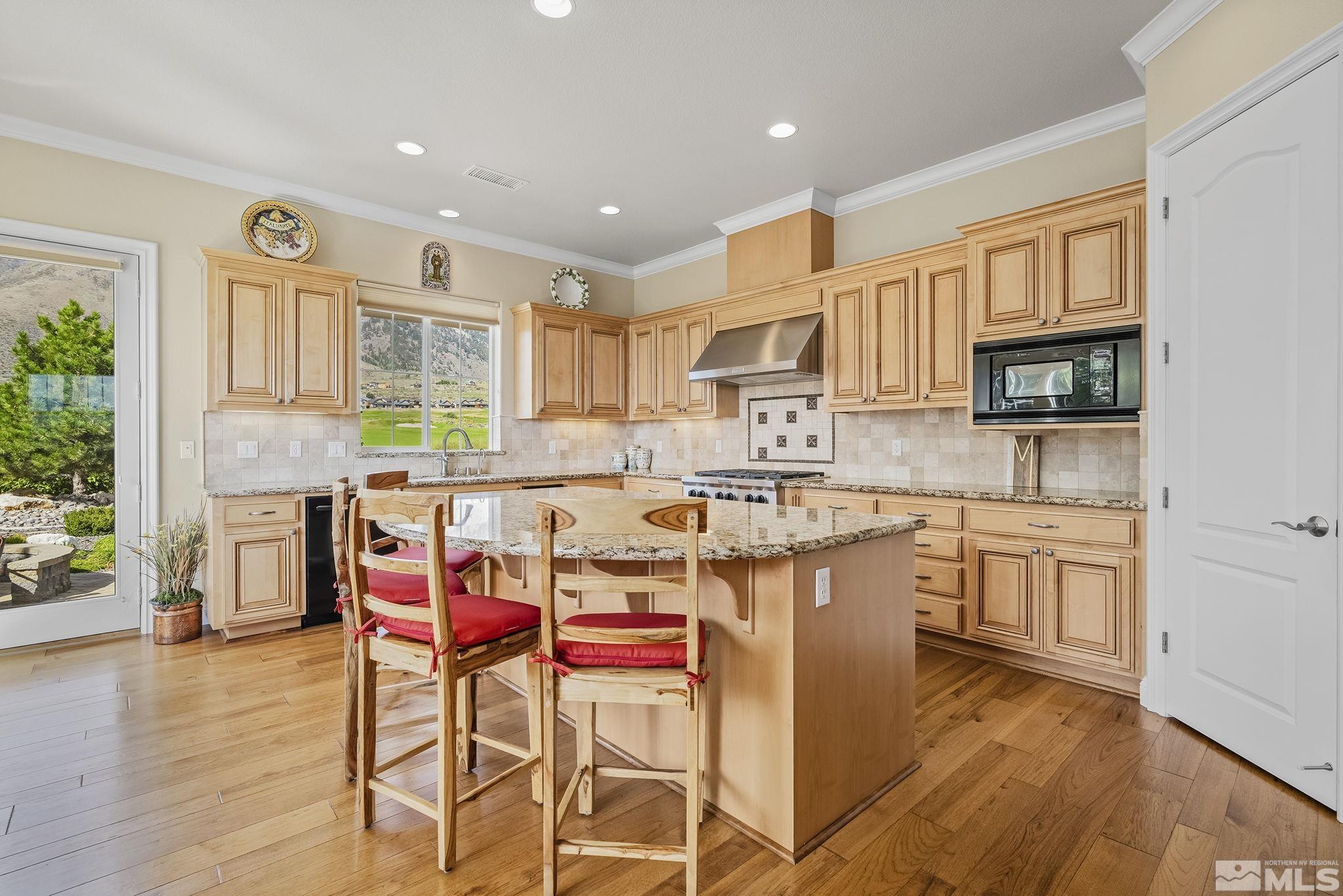 2892 Promontory Drive Genoa, NV 89411 - Photo 11 of 40 a kitchen with stainless steel appliances granite countertop a stove top oven a sink dishwasher and a dining table with wooden floor