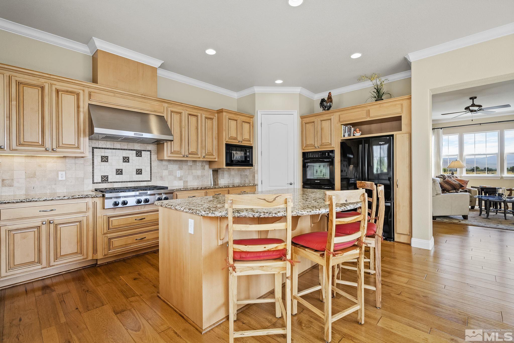 2892 Promontory Drive Genoa, NV 89411 - Photo 14 of 40 a kitchen with stainless steel appliances granite countertop a stove top oven a sink a dining table and chairs with wooden floor