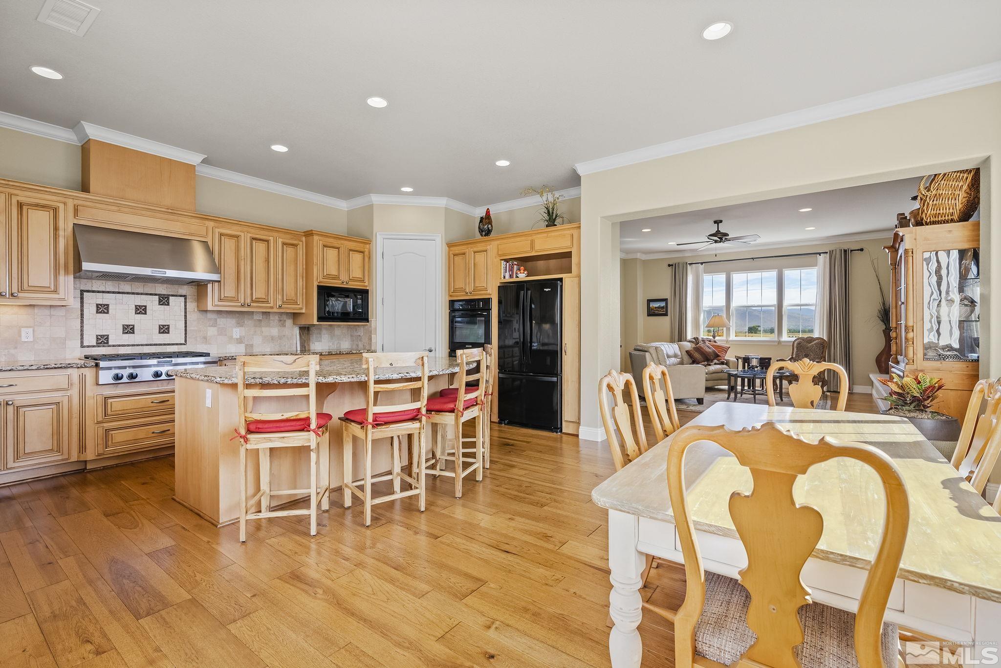 2892 Promontory Drive Genoa, NV 89411 - Photo 16 of 40 a kitchen with stainless steel appliances kitchen island granite countertop a refrigerator a stove a dining table and chairs with wooden floor