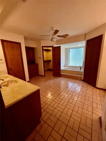 a view of an empty room with windows and chandelier fan