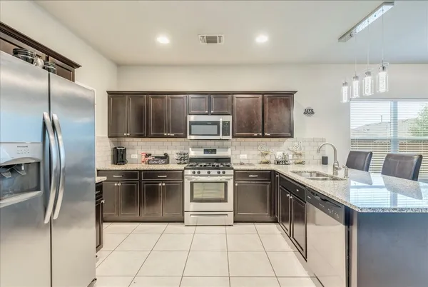 a kitchen with stainless steel appliances granite countertop a sink stove refrigerator and cabinets