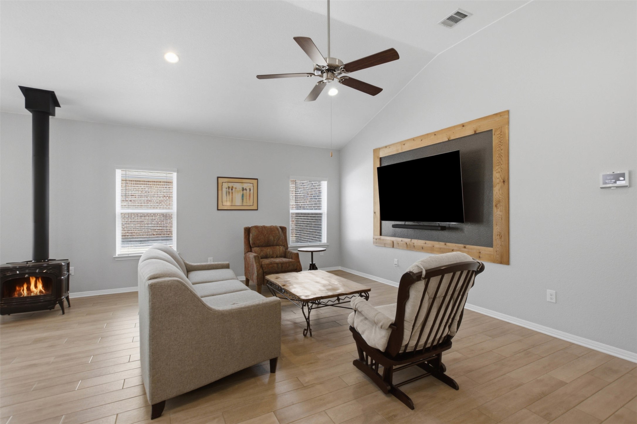 2413 Bridges Ranch Road Georgetown, TX 78628 - Photo 10 of 31 An inviting gathering space features vaulted ceilings and wood-look flooring, anchored by a charming wood-burning stove.