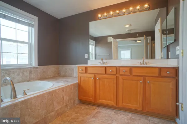 a bathroom with a bathtub a double vanity sink and a mirror