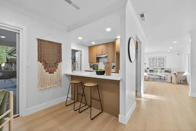 a living room with stainless steel appliances granite countertop furniture and a dining table with wooden floor