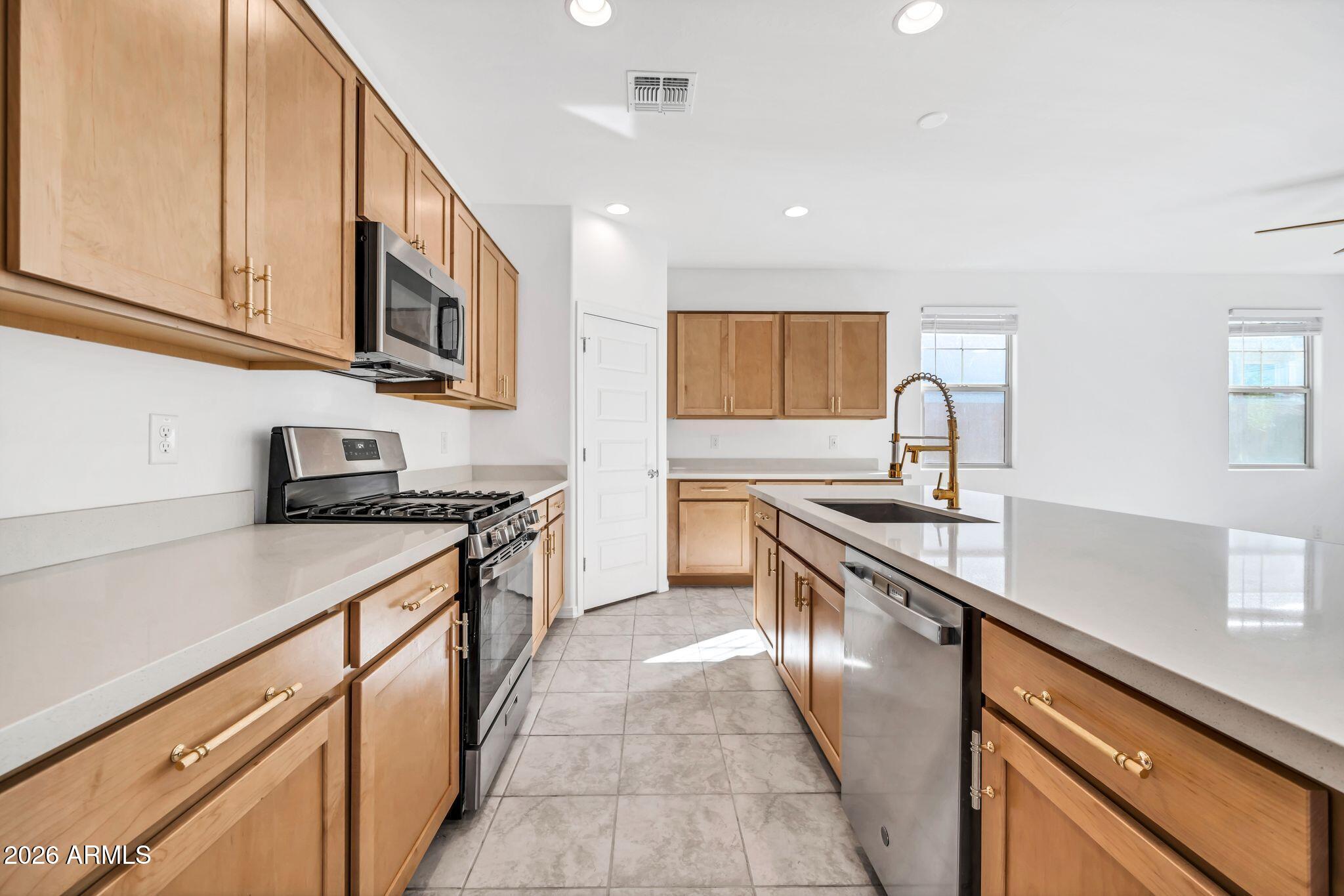 10223 West Piccadilly Road Avondale, AZ 85392 - Photo 3 of 35 a kitchen with stainless steel appliances granite countertop a sink and dishwasher a stove top oven with wooden floor