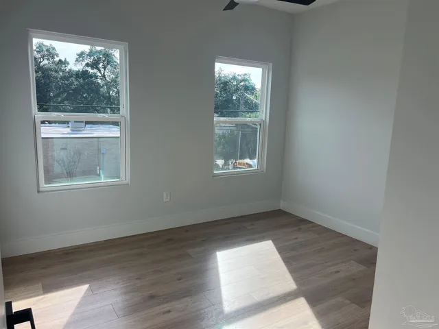 an empty room with wooden floor and windows