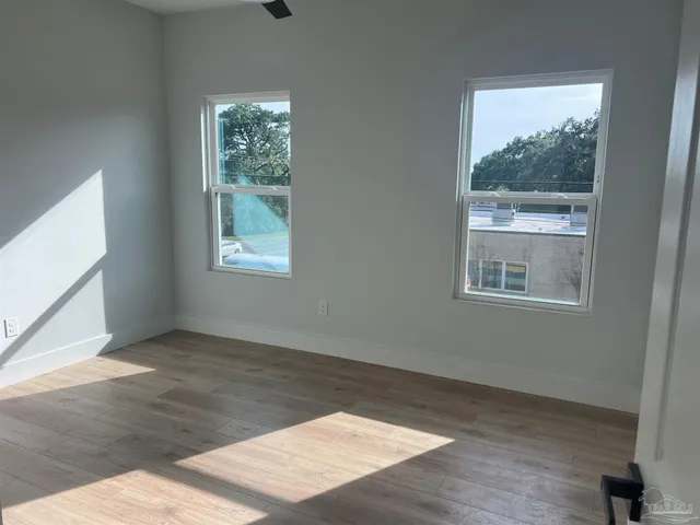 an empty room with wooden floor and windows