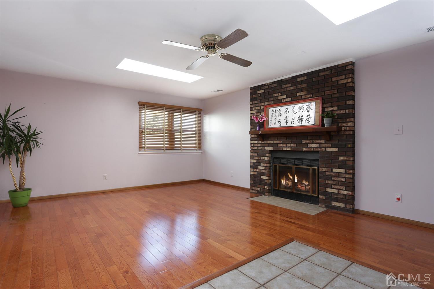 40 Azalea Drive Edison, NJ 08820 - Photo 21 of 36 an empty room with windows a fireplace and wooden floor