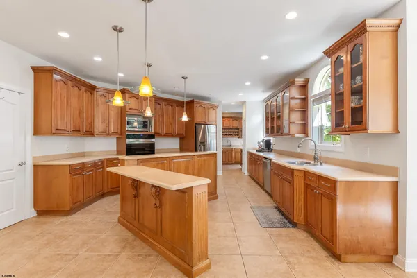 a large kitchen with kitchen island granite countertop a sink stainless steel appliances and cabinets