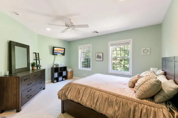 an empty room with chandelier fan and windows
