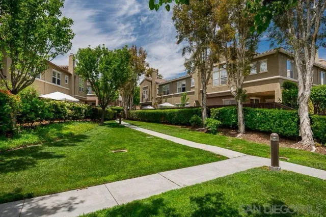 a view of a white house next to a yard with big trees