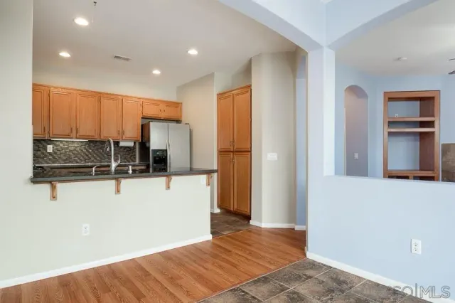 a view of kitchen with stainless steel appliances wooden floor and chair