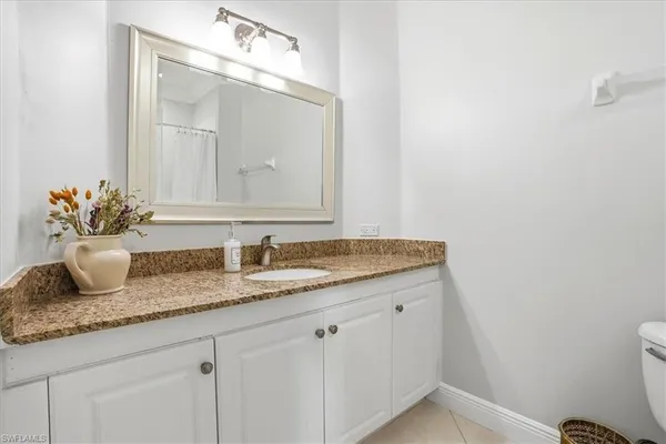 a bathroom with a granite countertop sink vanity mirror and toilet