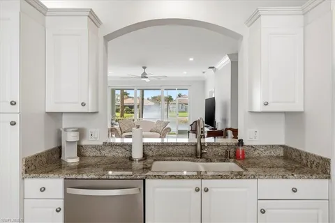 a kitchen with granite countertop a sink stainless steel appliances white cabinets and a granite counter tops