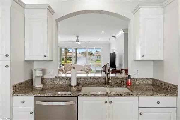 a kitchen with granite countertop a sink stainless steel appliances white cabinets and a granite counter tops
