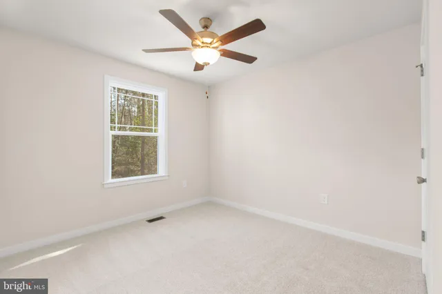an empty room with a window and a ceiling fan