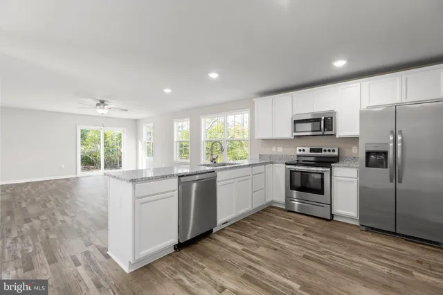 a kitchen with granite countertop white cabinets and stainless steel appliances