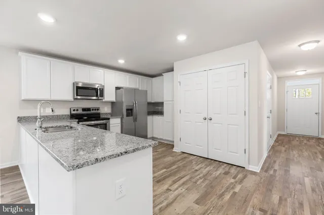 a kitchen with granite countertop stainless steel appliances a stove refrigerator sink and microwave