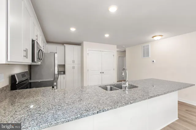 a kitchen with stainless steel appliances granite countertop a sink refrigerator and cabinets