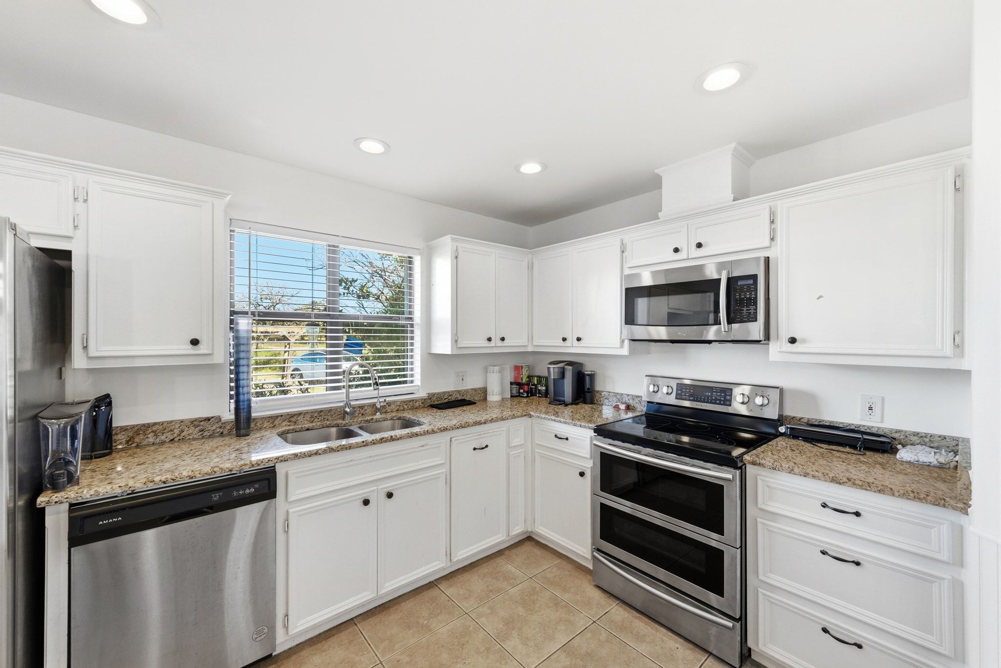 162 Farm To Market 672 Dale, TX 78616 - Photo 11 of 40 Kitchen featuring appliances with stainless steel finishes, white cabinets, light stone countertops, light tile patterned floors, and recessed lighting