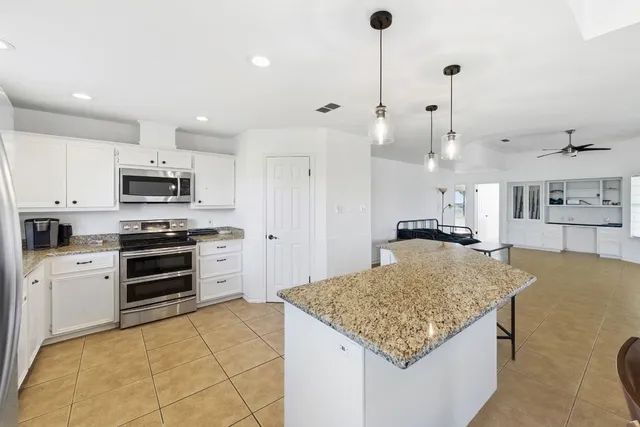 a kitchen with kitchen island granite countertop a stove a sink and a refrigerator