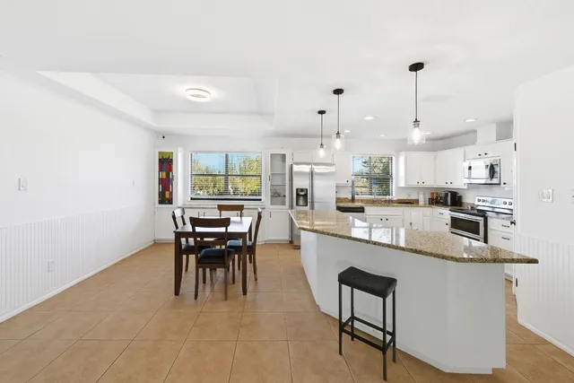 a kitchen with kitchen island a dining table and chairs