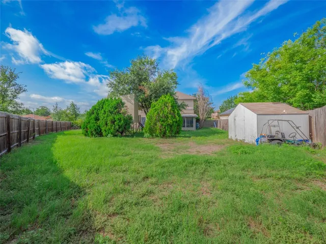 a view of a backyard with large trees and wooden fence