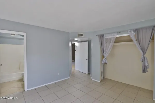 a view of an empty room with window and chandelier fan