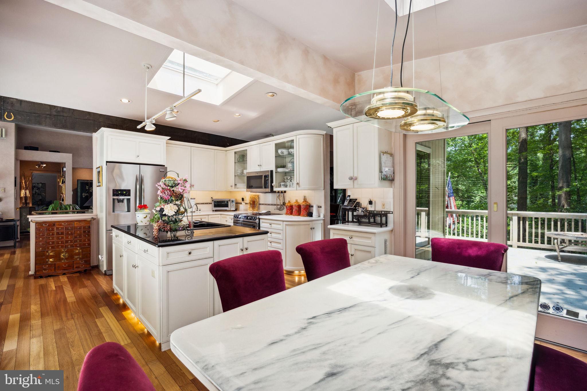100 Pugh Road Wayne, PA 19087 - Photo 24 of 57 a kitchen with granite countertop a stove a sink dishwasher a dining table and chairs with wooden floor