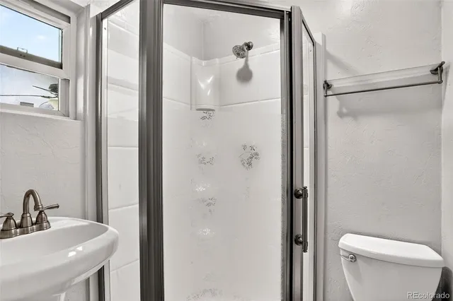 a bathroom with a shower a sink and a toilet